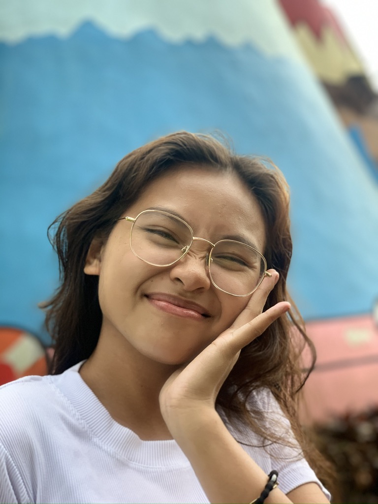 Yolyn tilting her head and smiling, mural behind her